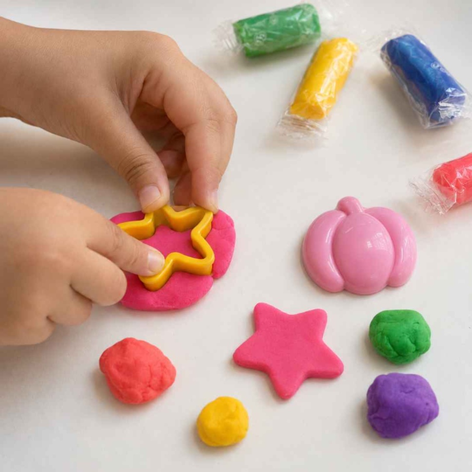 Mâinile unui copil folosesc forma stea pentru a modela plastilina