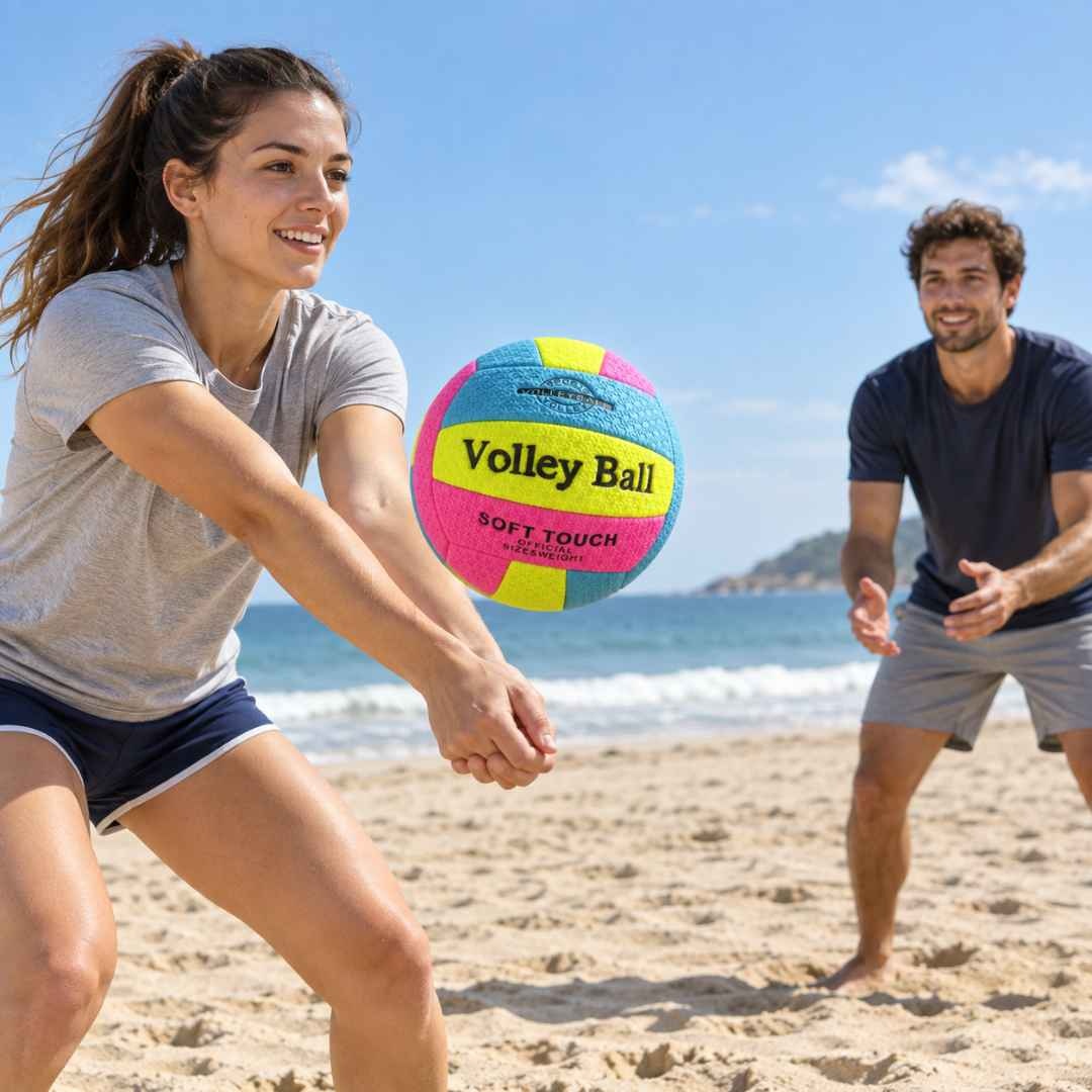 Doi adulți care joacă volei cu mingea soft touch pe nisip, lângă mare